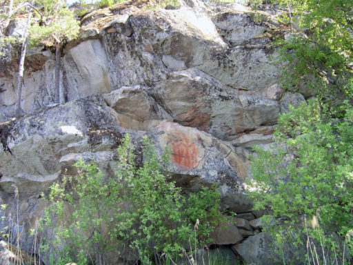 Kolmiköytisien kalliomaalaus jyrkässä kallioseinämässä.