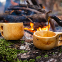 wooden finnish mug, called Kuksa on the stump, with camp fire